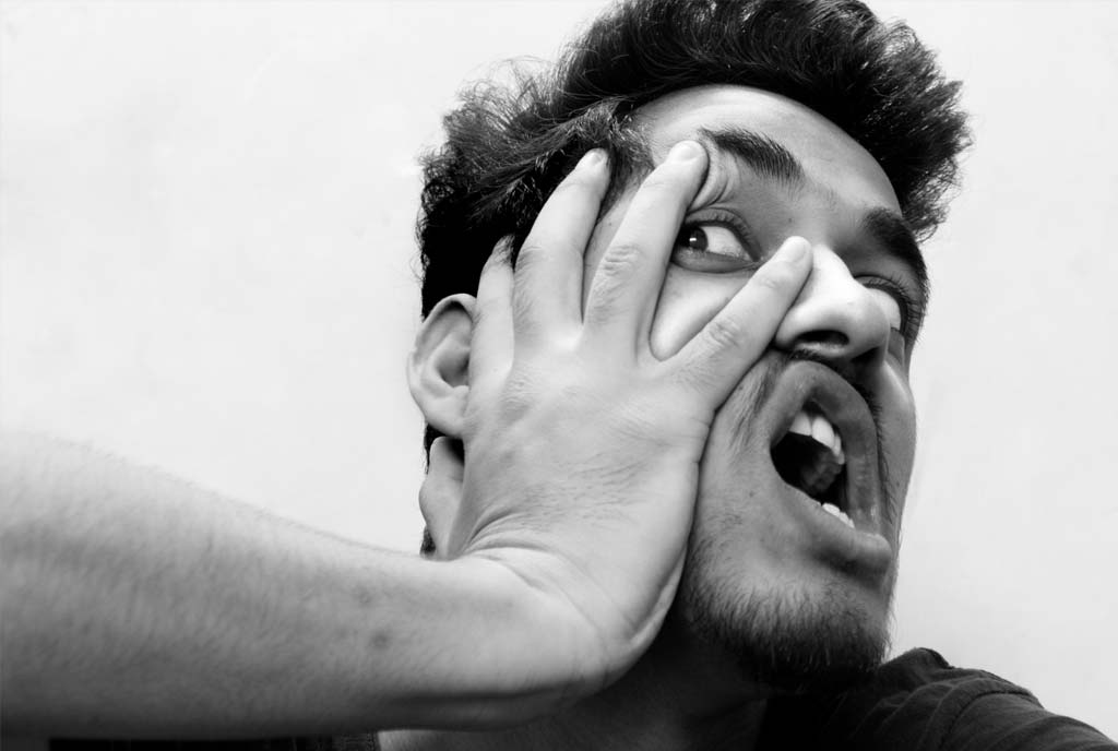 A man's face is stopped by a hand